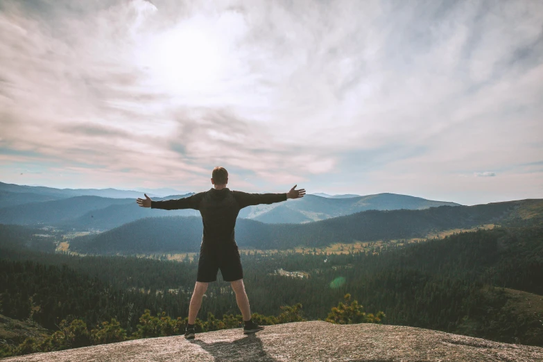 a man standing on top of a hill with his arms spread wide