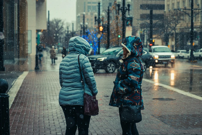 two girls stand on the sidewalk and talk