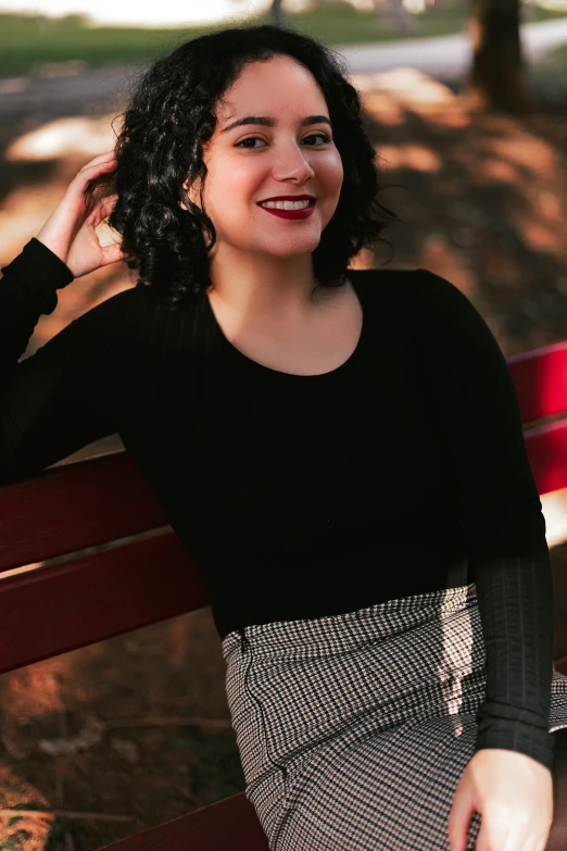 a smiling woman sitting on a bench posing for a picture