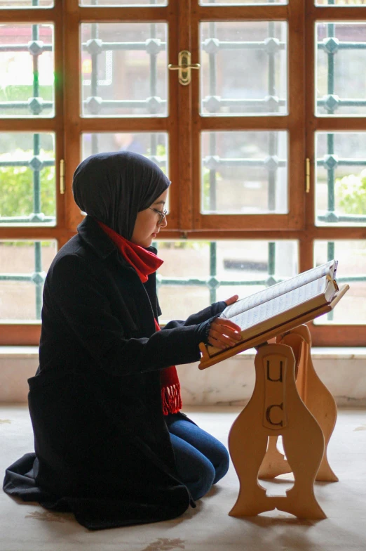 the woman is sitting down on the floor reading a book