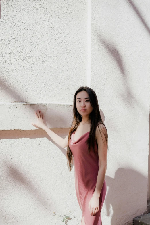 a girl posing in front of a wall and her arm extended
