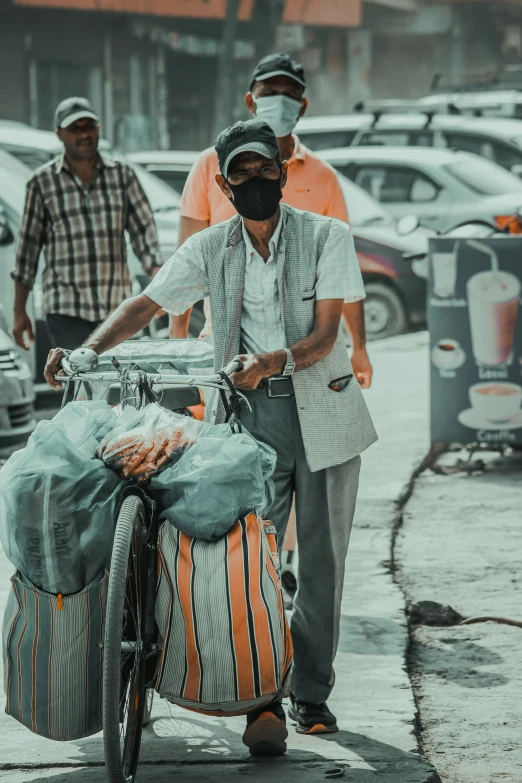 two men walking their bikes carrying groceries