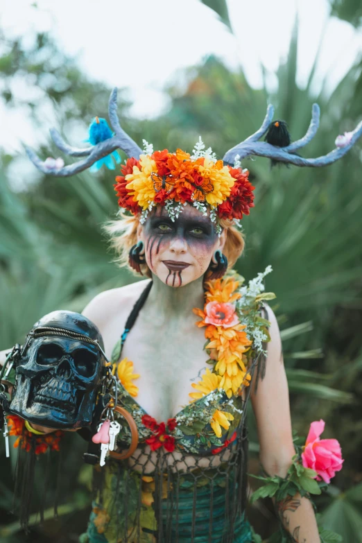 woman with horns holding black object, helmet and flowers