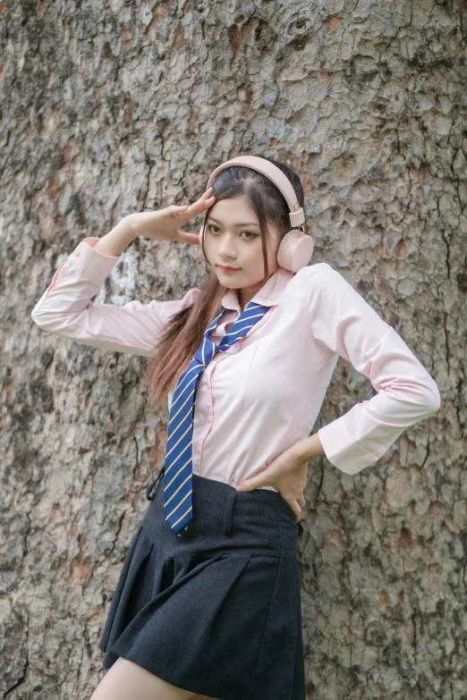 a young asian girl with headphones is wearing a skirt and shirt