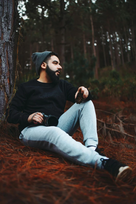 a man sitting on the ground near a forest