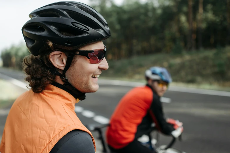 two people in helmets and vests on bicycles on street