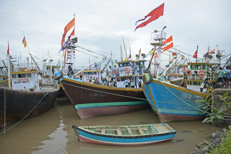 boats lined up on the shore with flags flying in the background