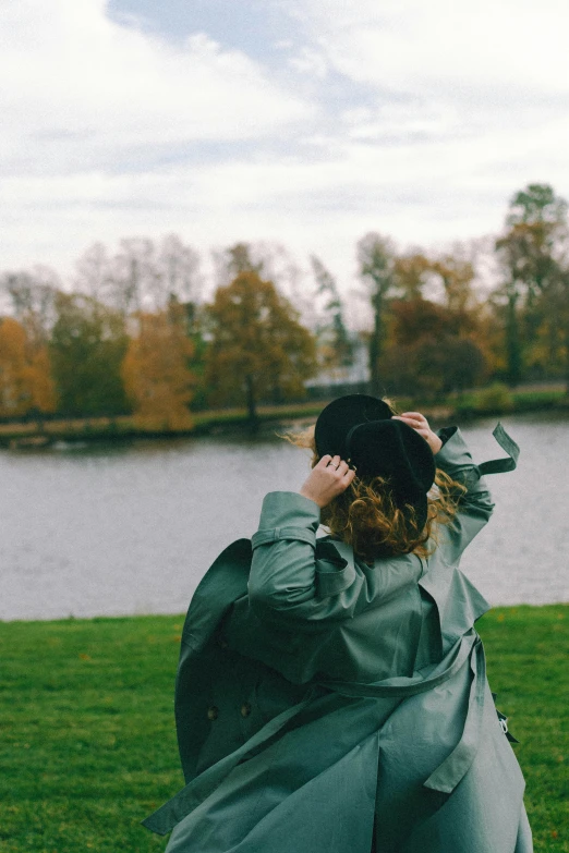 a person in a green coat and hat with a black bag