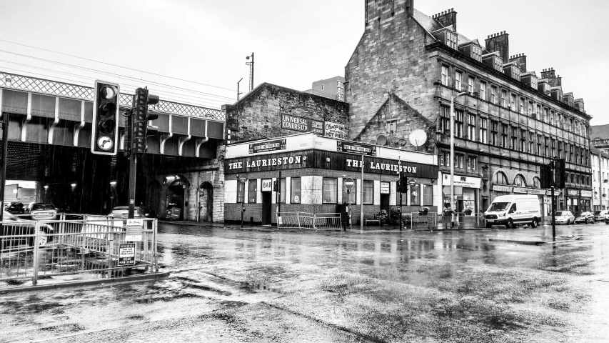 a wet street with a building and a stop light on the corner