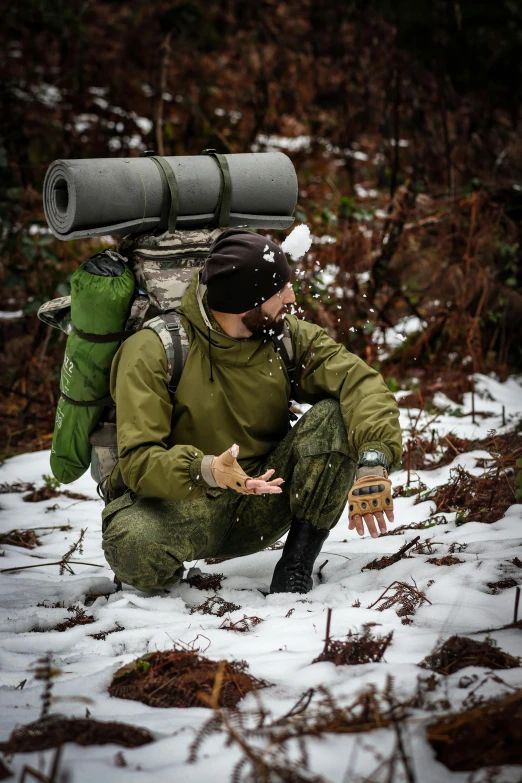 a man kneeling down with a backpack on his back