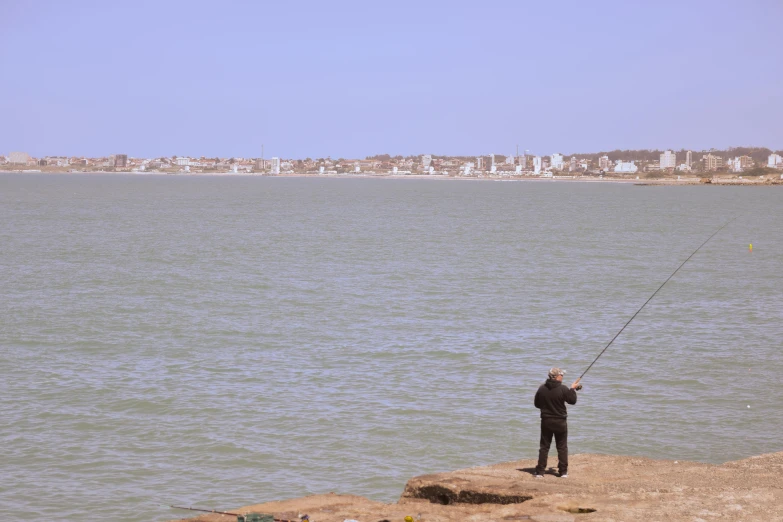 a person is fishing in the water from the shore