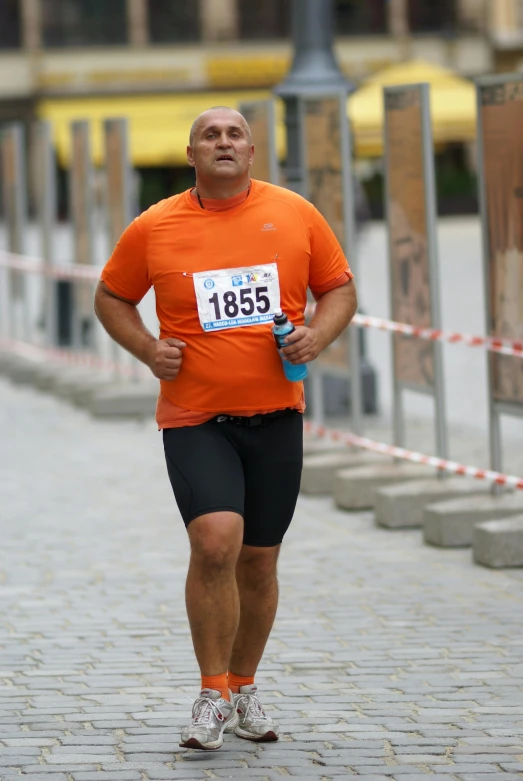 a man in an orange shirt is running in a race