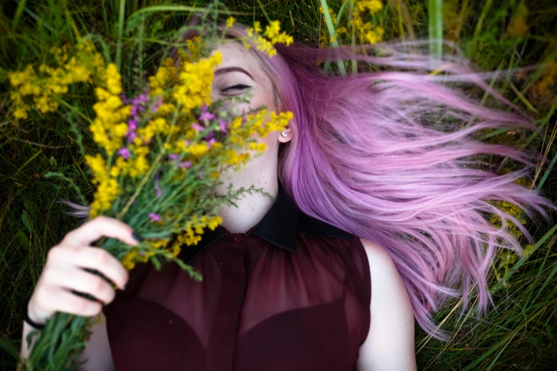 a woman with long hair laying on the ground holding flowers