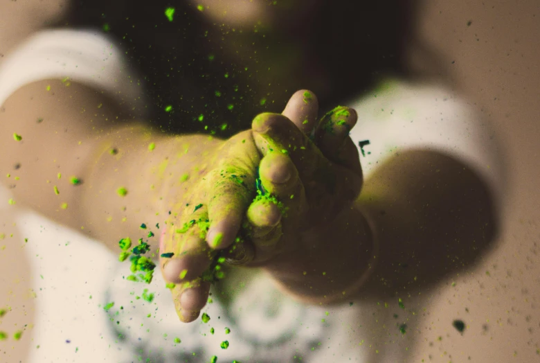 a young man holding his fingers full of green confetti