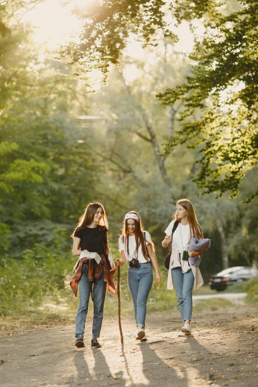 a group of girls standing on top of a dirt road