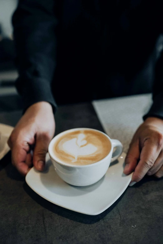 someone's hand holding a cup of latte