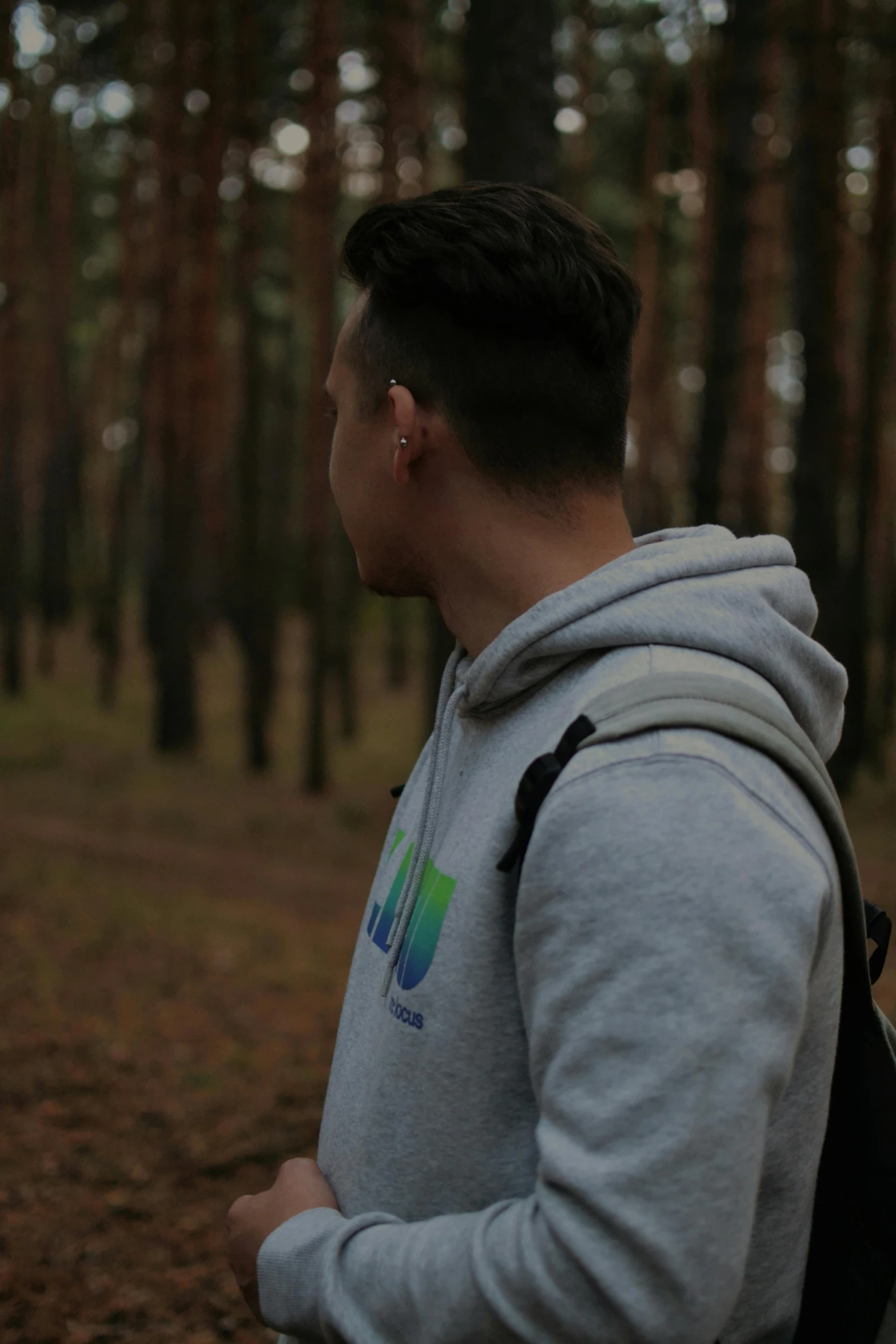 a young man standing in a wooded area with trees