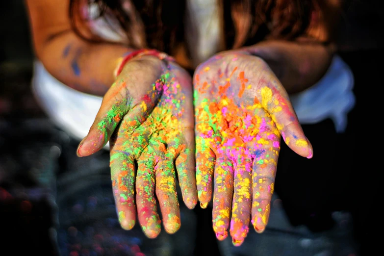 a person with their hands covered in colorful paint