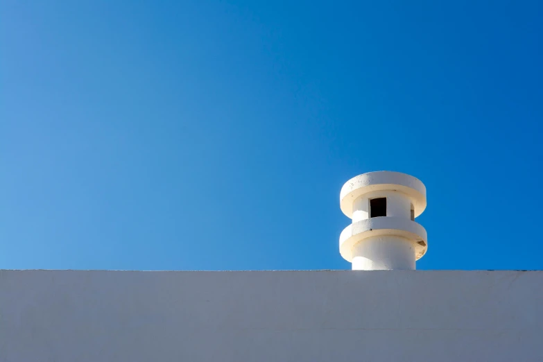 a white wall and a clock against a blue sky