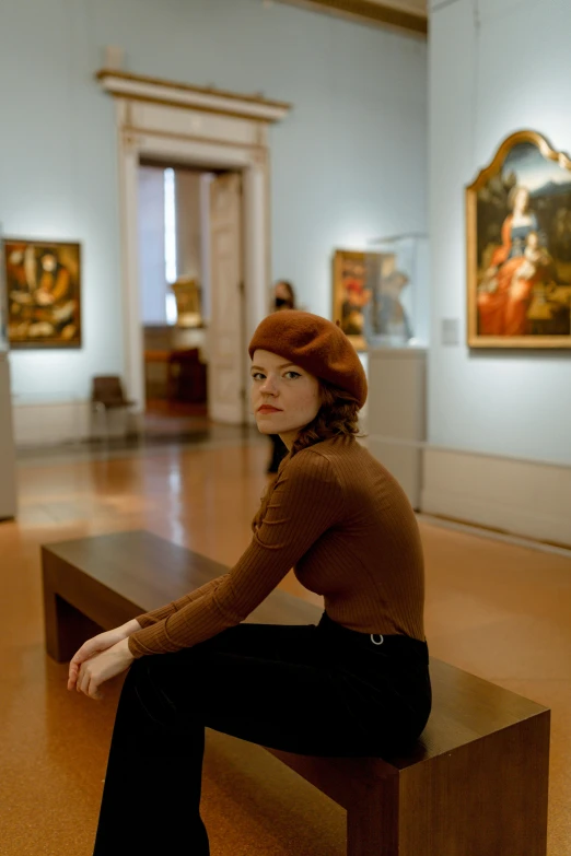 the woman is sitting on the bench by the paintings