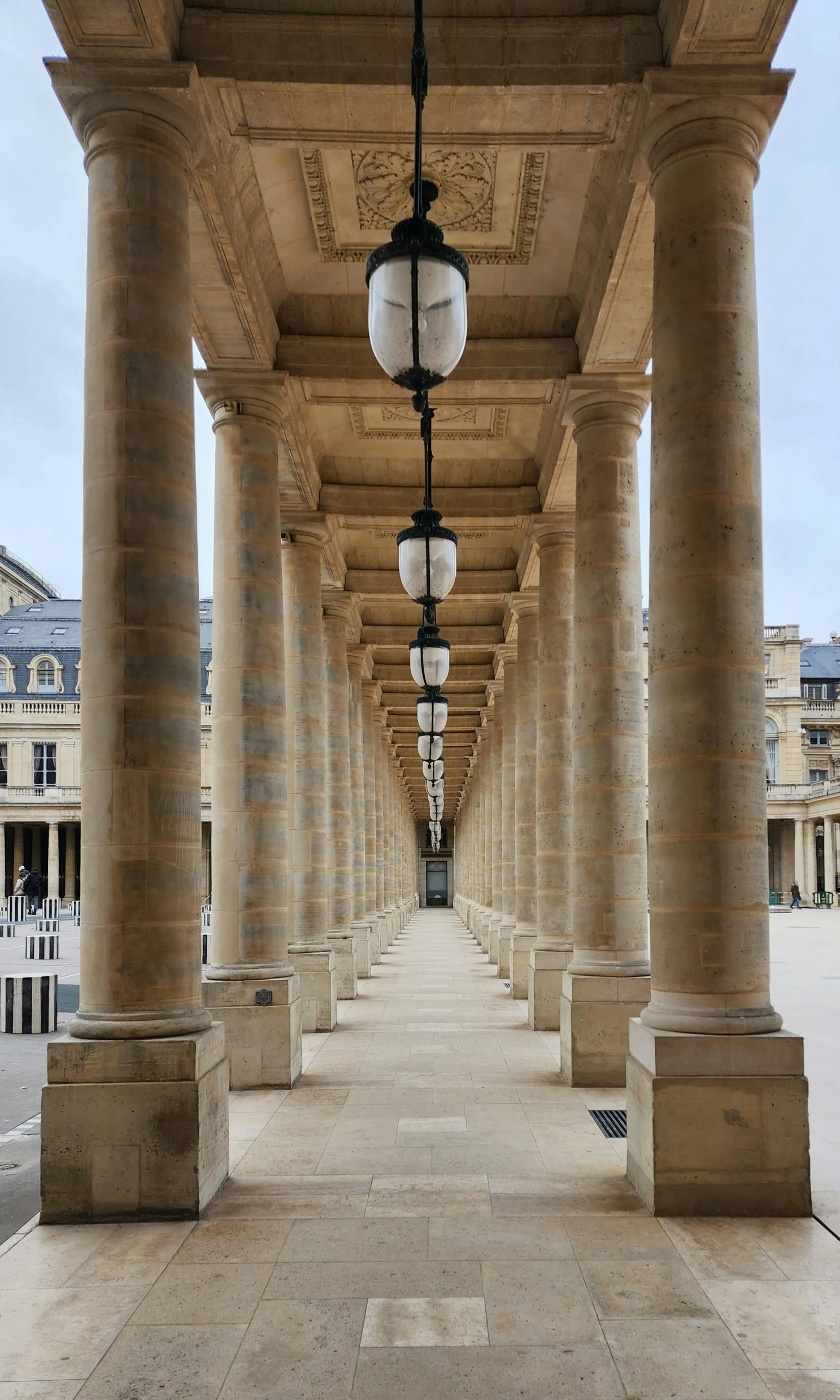 a sidewalk with large columns and lantern lights on the sides