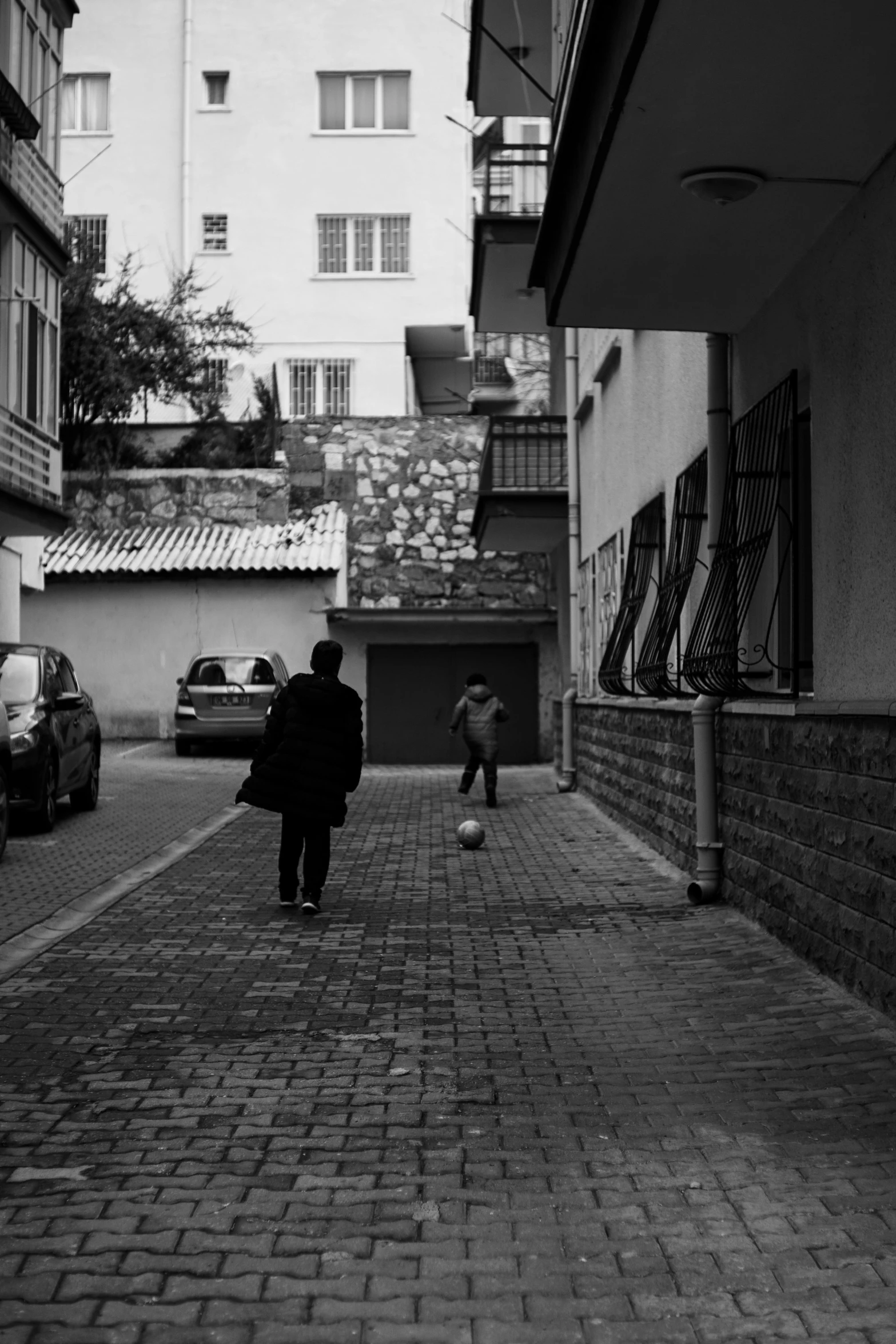 a person walking down a street near parked cars