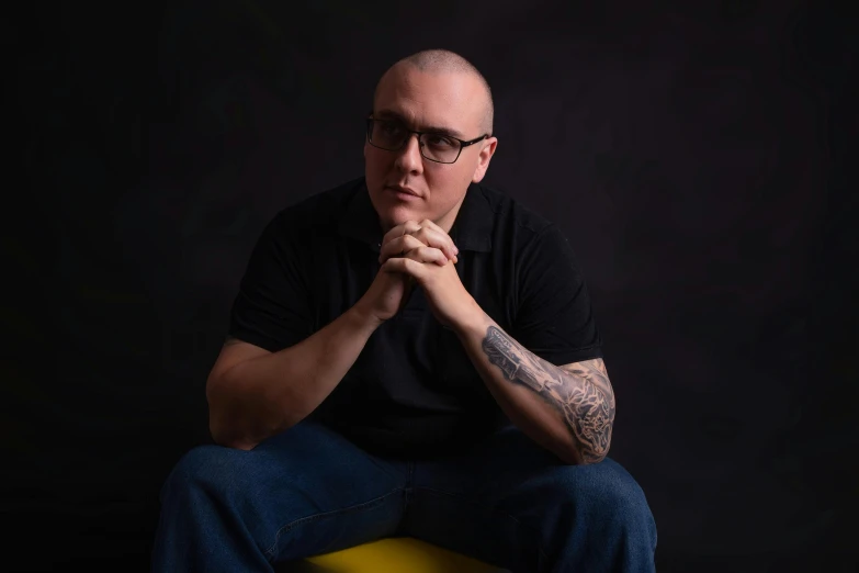 a bald headed man sitting on a stool