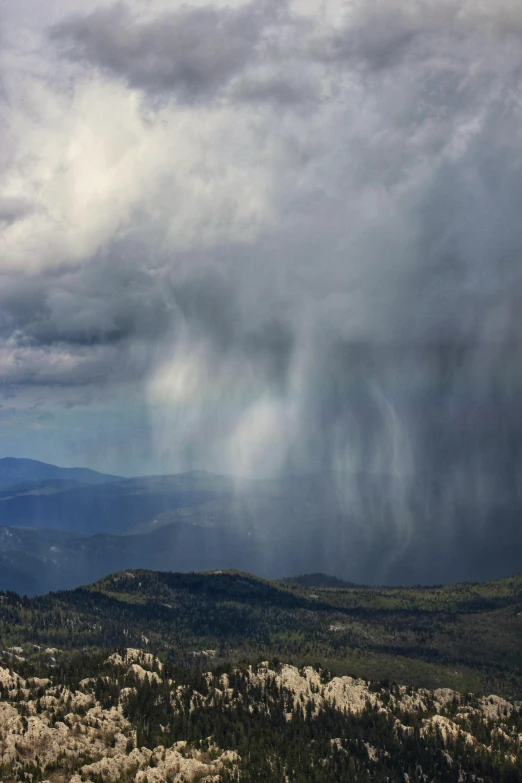 the storm clouds loom overhead over a hilly mountain valley