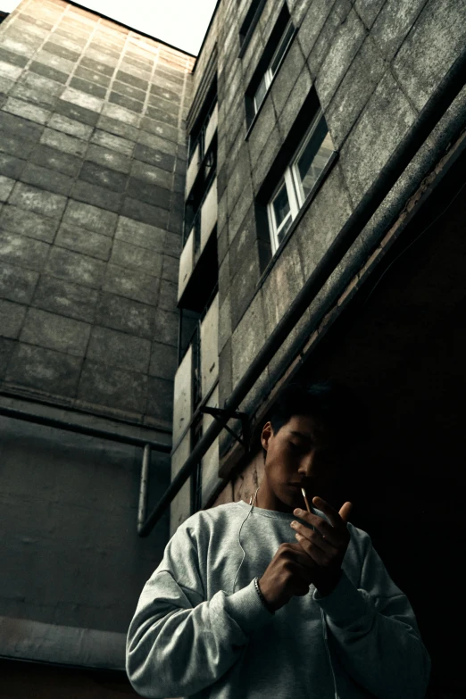 a man smoking his cigarette in front of a brick building