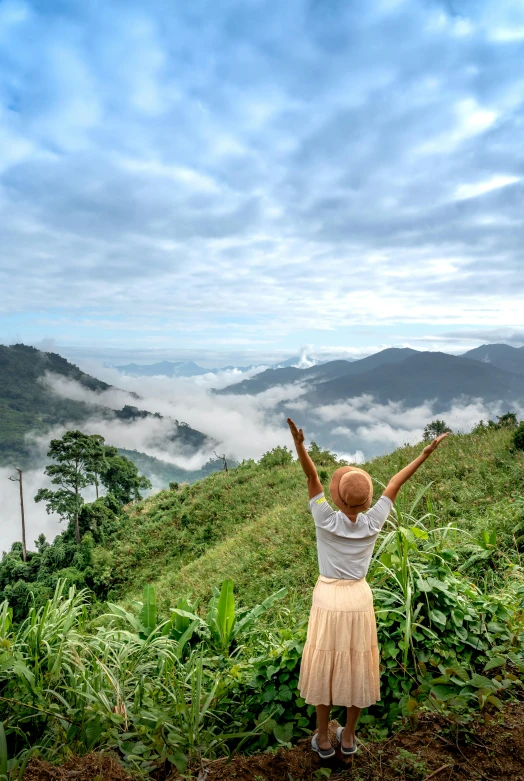 a woman with her arms outstretched stands on top of a hill