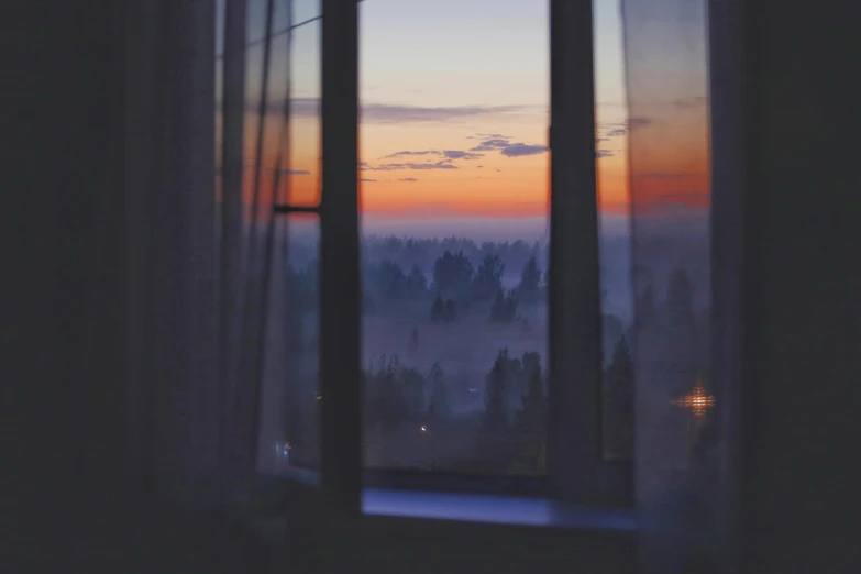 the view out of an open window overlooking fog and a sunset