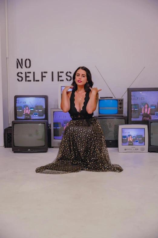 there is a woman in a dress standing next to a number of televisions