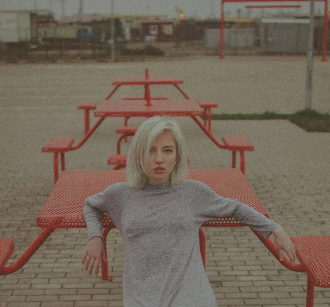 a woman stands in front of two tables with red chairs