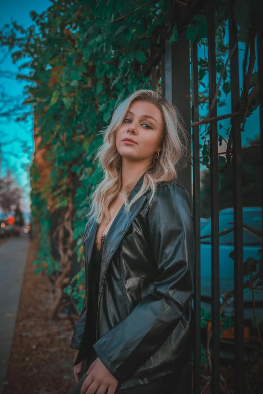 a woman in black jacket leaning against iron fence