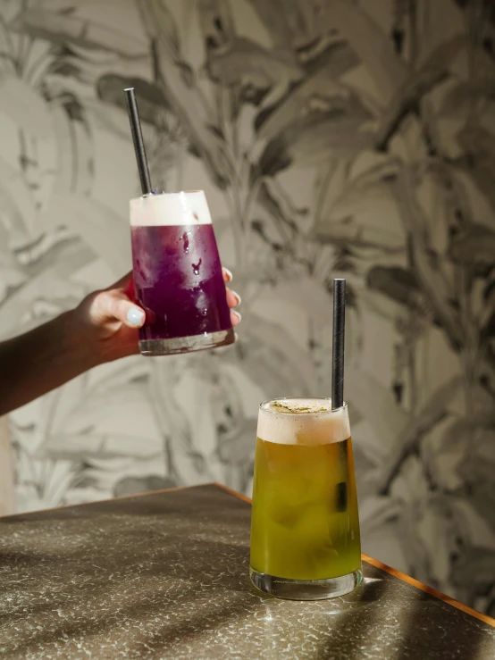 two drinks on the table being held up to a woman