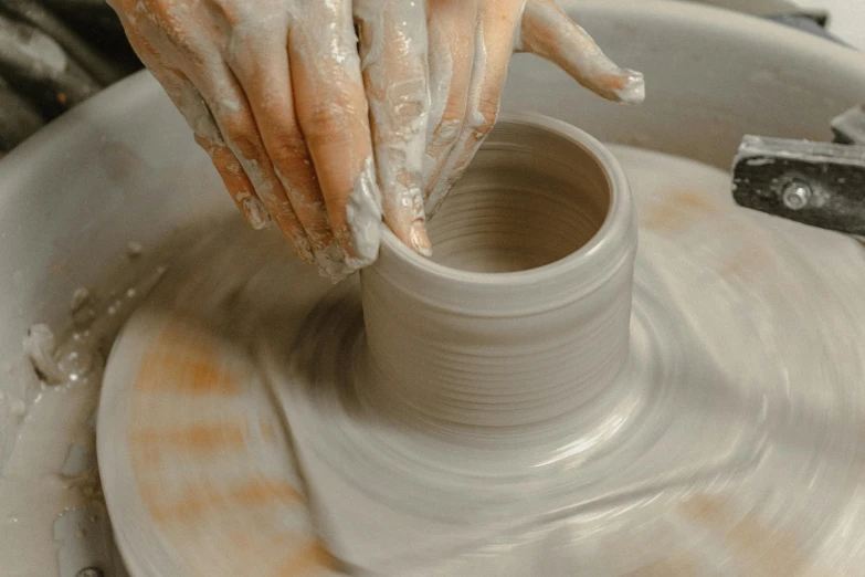 someone uses pottery with their hands on a wheel