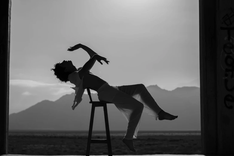 a girl in an artistic pose on top of a stool