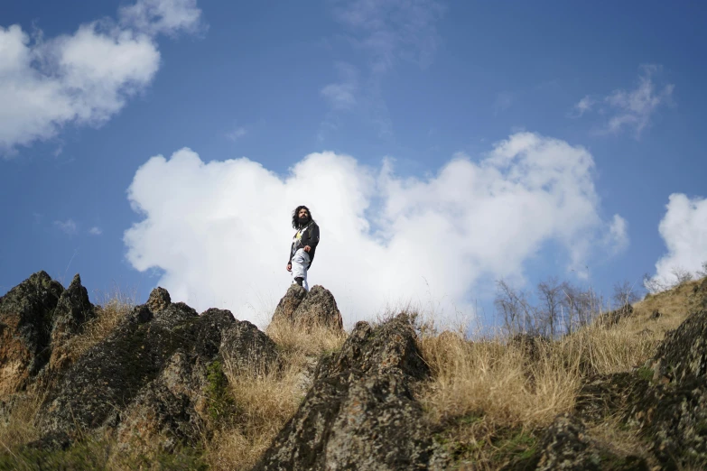 the lone woman stands atop a rocky mountain