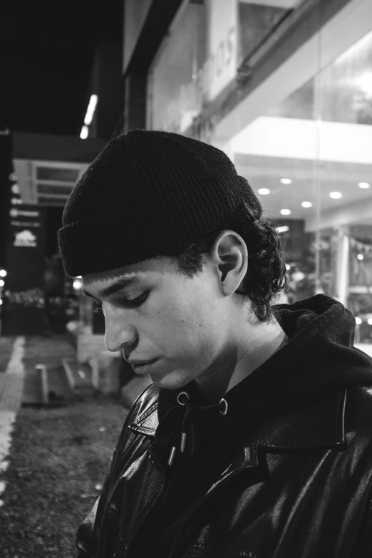 black and white po of a man in a beanie looking at his phone