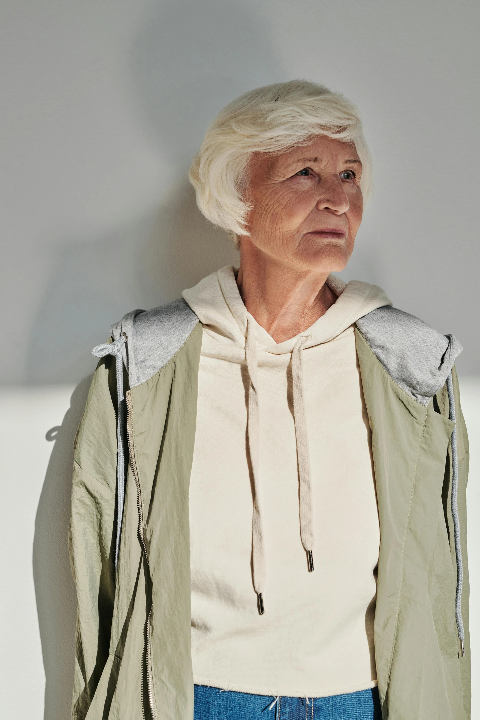 an old woman with white hair in a white and green jacket