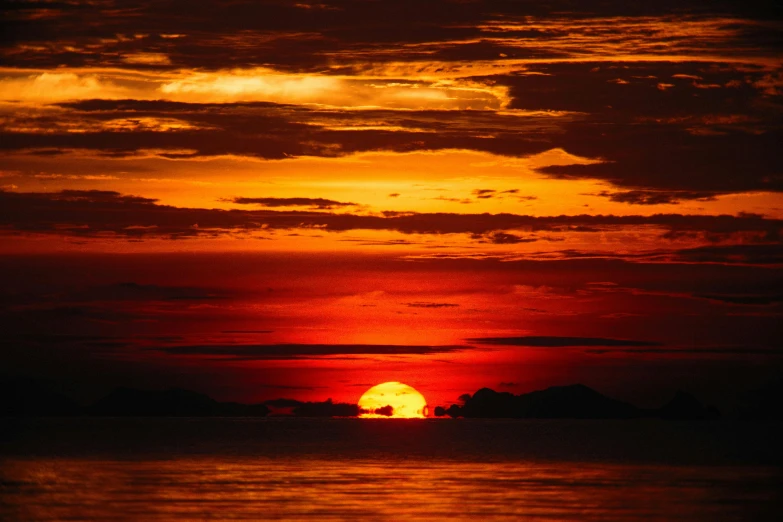 the sunset in red and orange colors over calm water