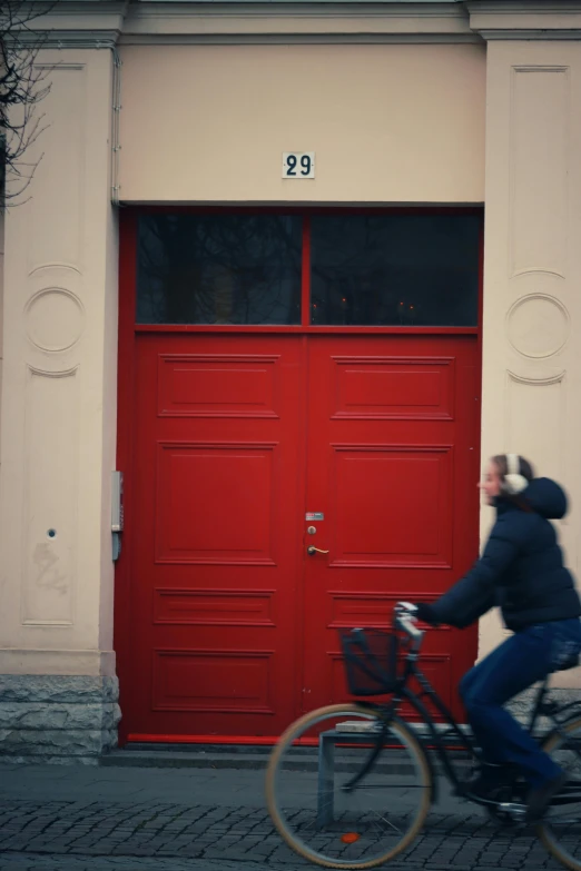 a person riding a bicycle down a street past a red door