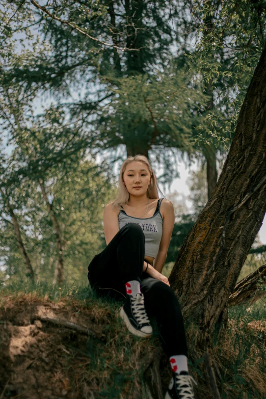 a woman sitting on a tree trunk near a forest