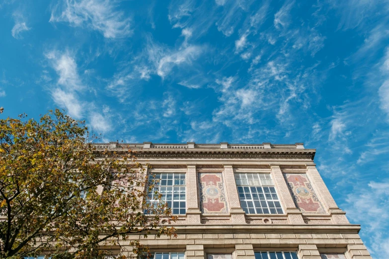 a building and tree in front of blue sky with some clouds