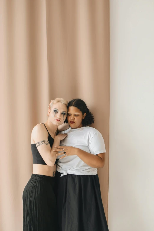 two women pose against the wall with their arms around each other