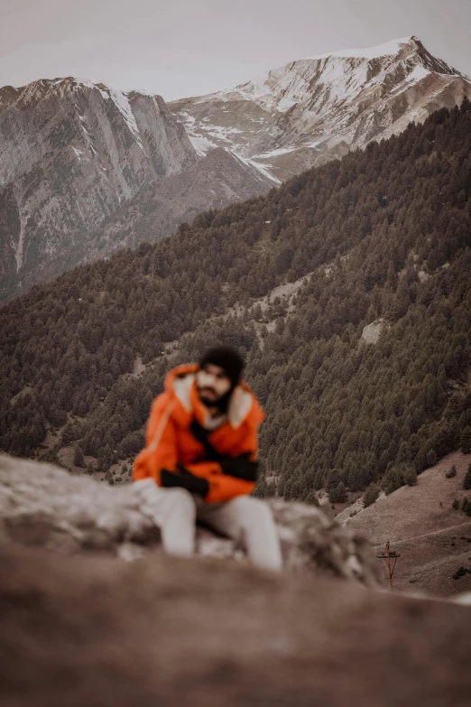 a man in orange is standing on the edge of a hill