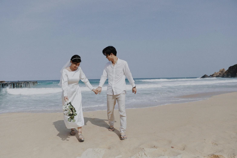 man and woman walking on beach holding hands