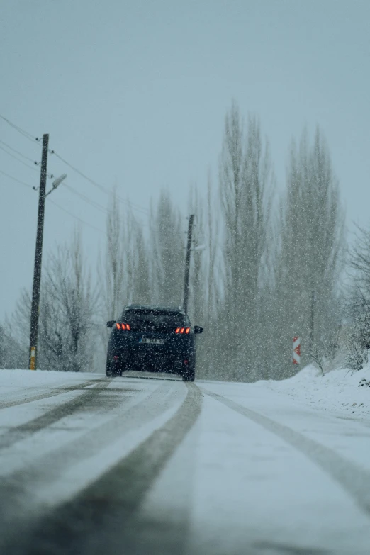 a snow covered road with a car at the traffic light