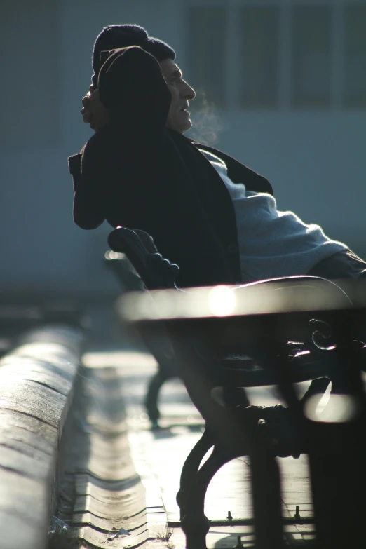 a man sitting at a park bench with his head resting on a cigarette