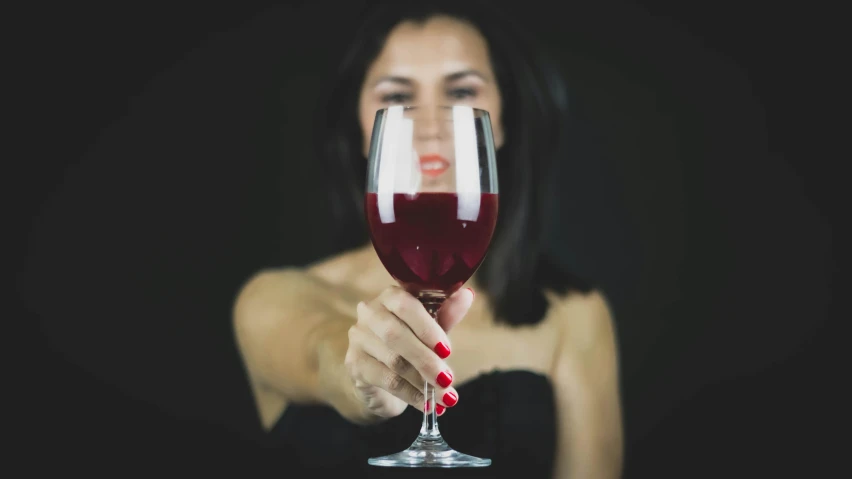 woman holding a glass of red wine to her face